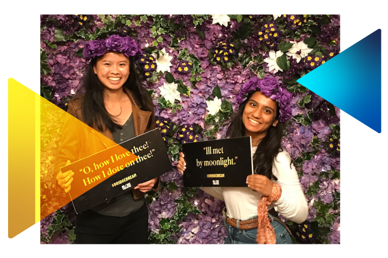 Two students holding signs with quotes in front of a flower wall