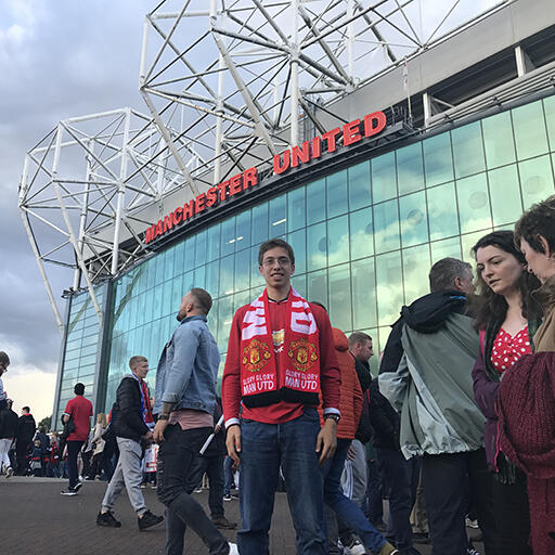 Student Noah Prozan in front of Old Trafford Stadium wearing Manchester United gear